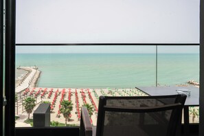 Un balcon donnant sur une plage où l’on peut voir des rangées de parasols et de chaises.