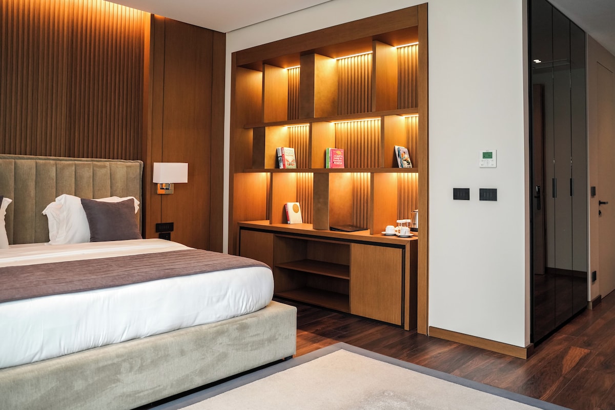 Een moderne hotelkamer met een groot bed, ingebouwde houten planken, een bureau en een inloopkast.