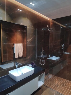 Un baño moderno con dos lavamanos, un espejo grande y una ducha.