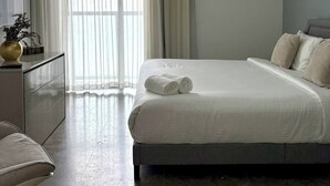 Une chambre à coucher moderne avec un grand lit, une table de chevet, une chaise et une fenêtre avec des rideaux.