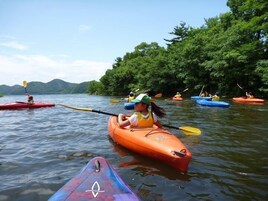 Un grupo de personas haciendo kayak en un río tranquilo bordeado de vegetación exuberante.