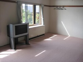 Una habitación con ventana, un radiador y un televisor sobre un mueble.