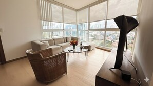 Ein modernes Wohnzimmer mit einer Couch, einem Couchtisch und einem großen Fenster mit Blick auf die Stadt.
