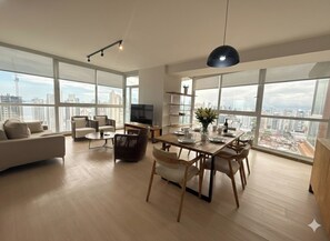 A spacious living room with a dining area, large windows, and a city view. - Stunning 3BR with Views, Balcony and Parking (Panamá)