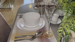 Un salon moderne avec un coin repas aménagé pour un repas, comprenant un canapé, une table basse et un téléviseur fixé au mur.