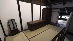 Ein Raum mit Tatami-Matten, einer hölzernen Sitzbank, einem Spiegel und einer Schiebetür.