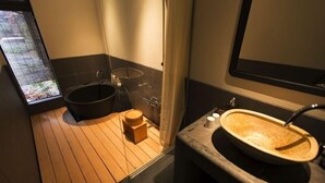 Ein modernes Badezimmer mit Holzboden, einer schwarzen Badewanne, einem Holzwaschbecken und einer Duschkabine aus Glas.