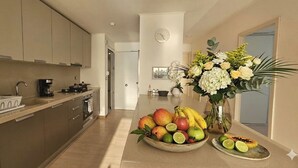 Une cuisine moderne équipée d’un four à micro-ondes, d’une cuisinière et d’un évier. On peut voir un saladier rempli de fruits et un vase de fleurs sur le plan de travail.