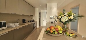A modern kitchen with a microwave, stove, and sink. There is a bowl of fruit and a vase of flowers on the counter. - Stunning 3BR with Views, Balcony and Parking (Panamá)