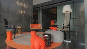 A modern interior with a round orange rug, a black leather chair, a red sofa, a white ottoman, and a floor lamp. - Exclusive and luxury 1BR with balcony in Yoo Panama (Panama City)