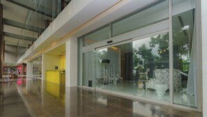 A modern interior with a glass storefront, a reception desk, and a seating area with white furniture. - Exclusive and luxury 1BR with balcony in Yoo Panama (Panama City)