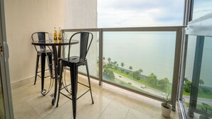 Un balcone con vista su uno specchio d'acqua, un tavolo con sedie e una pianta in vaso.