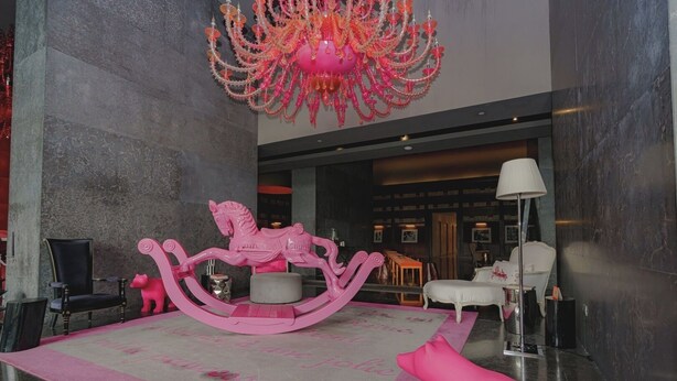 Una hall con un cavallo a dondolo rosa, un lampadario e un divano bianco.
