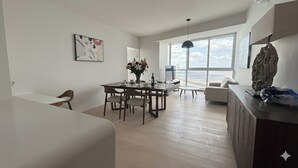 Una sala de estar moderna con comedor, ventanas grandes y vista al mar.