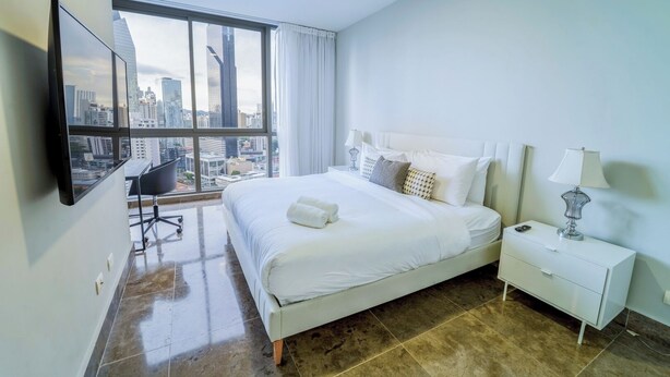 Ein modernes Hotelzimmer mit einem großen Bett, einem Schreibtisch und Blick auf die Stadt.