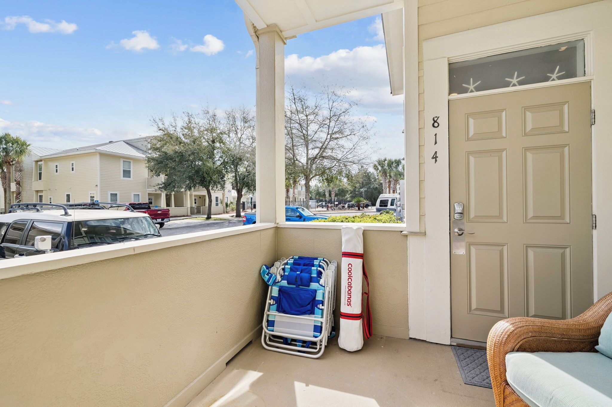 A balcony with a beach chair, a stroller, and a door with the number 814.