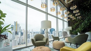 A modern lounge with large windows, comfortable seating, and a city view. - Exclusive and Luxurious 2BR at Wanders and Yoo (Panama City)