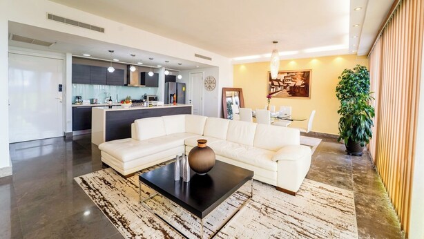 A modern living room with a white sofa, a black coffee table, and a large potted plant. - Exclusive and luxury 1BR with balcony in Yoo Panama (Panamá)