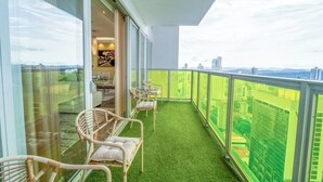 A balcony with artificial grass, wicker chairs, and a glass door leading to an interior space with a dining table and chairs. - Exclusive and luxury 1BR with balcony in Yoo Panama (Panamá)