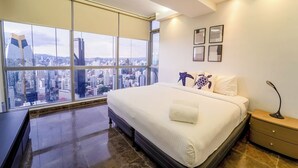 A modern bedroom with a large bed, city view, and minimal decor. - Exclusive and luxury 1BR with balcony in Yoo Panama (Panamá)