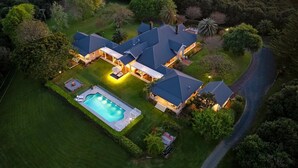 A large house with a swimming pool, surrounded by lush greenery and a winding driveway. - Hinterland House (NSW)