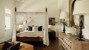 A bedroom with a four-poster bed, bedside lamps, a wooden dresser, and a mirror. - Hinterland House (NSW)