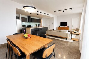 A modern apartment with a dining area, kitchen, living room, and a TV. - Exclusive and cozy 1BR balcony in Yoo Panama (Panamá)