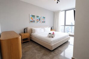 Ein Hotelzimmer mit Bett, Nachttischen, einem Holztischchen, Blick auf die Stadt und Kunstwerken an der Wand.