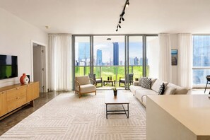A modern living room with a large window, a flat-screen TV, a sofa, a coffee table, and a wooden cabinet. - Exclusive and cozy 1BR balcony in Yoo Panama (Panamá)