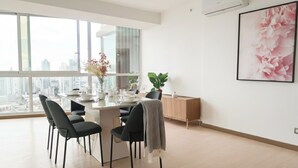 A modern dining area with a large window, a dining table set for four, and a view of the cityscape. - Stunning 3BR with Views, Balcony and Parking (Panamá)