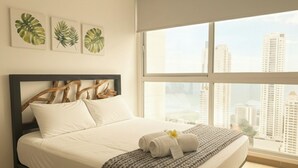 A bedroom with a bed, a window with a city view, and three framed leaves on the wall. - Stunning 3BR with Views, Balcony and Parking (Panamá)