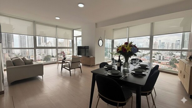 A modern apartment with a dining area, a living room, and a TV. - Stunning 3BR with Views, Balcony and Parking (Panamá)