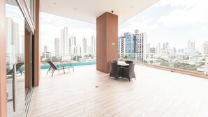 A spacious balcony with a view of a city skyline, a pool, and outdoor furniture. - Stunning 3BR with Views, Balcony and Parking (Panamá)