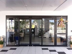 A modern building entrance with glass doors, a tiled floor, and potted plants. - Hotel De L Aqua (Miyakojima)