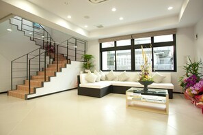 A modern living room with a staircase, a sofa set, a coffee table, and large windows. - Hotel De L Aqua (Miyakojima)