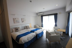 A hotel room with two beds, a desk, a chair, and a window with curtains. - Hotel De L Aqua (Miyakojima)