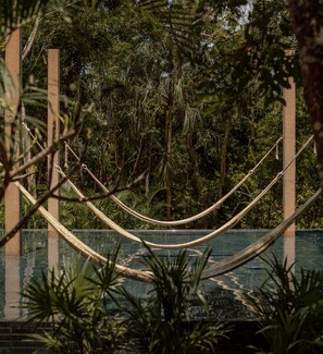 Una hamaca sobre una piscina con vista a una vegetación densa.