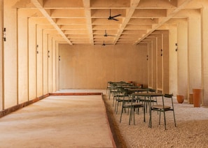 Una habitación de diseño alargado y estrecho, con varios ventiladores de techo y filas de sillas.