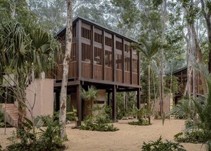 Una estructura moderna de madera con varios niveles, rodeada de exuberante vegetación tropical.