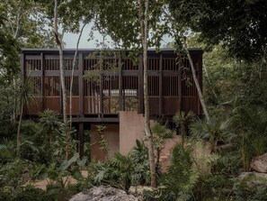 Un edificio moderno con diseño minimalista, rodeado de exuberante vegetación tropical.
