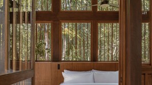 A room with a bed, wooden paneling, and large windows with a view of greenery. - Boca De Agua Bacalar (Felipe Carrillo Puerto)