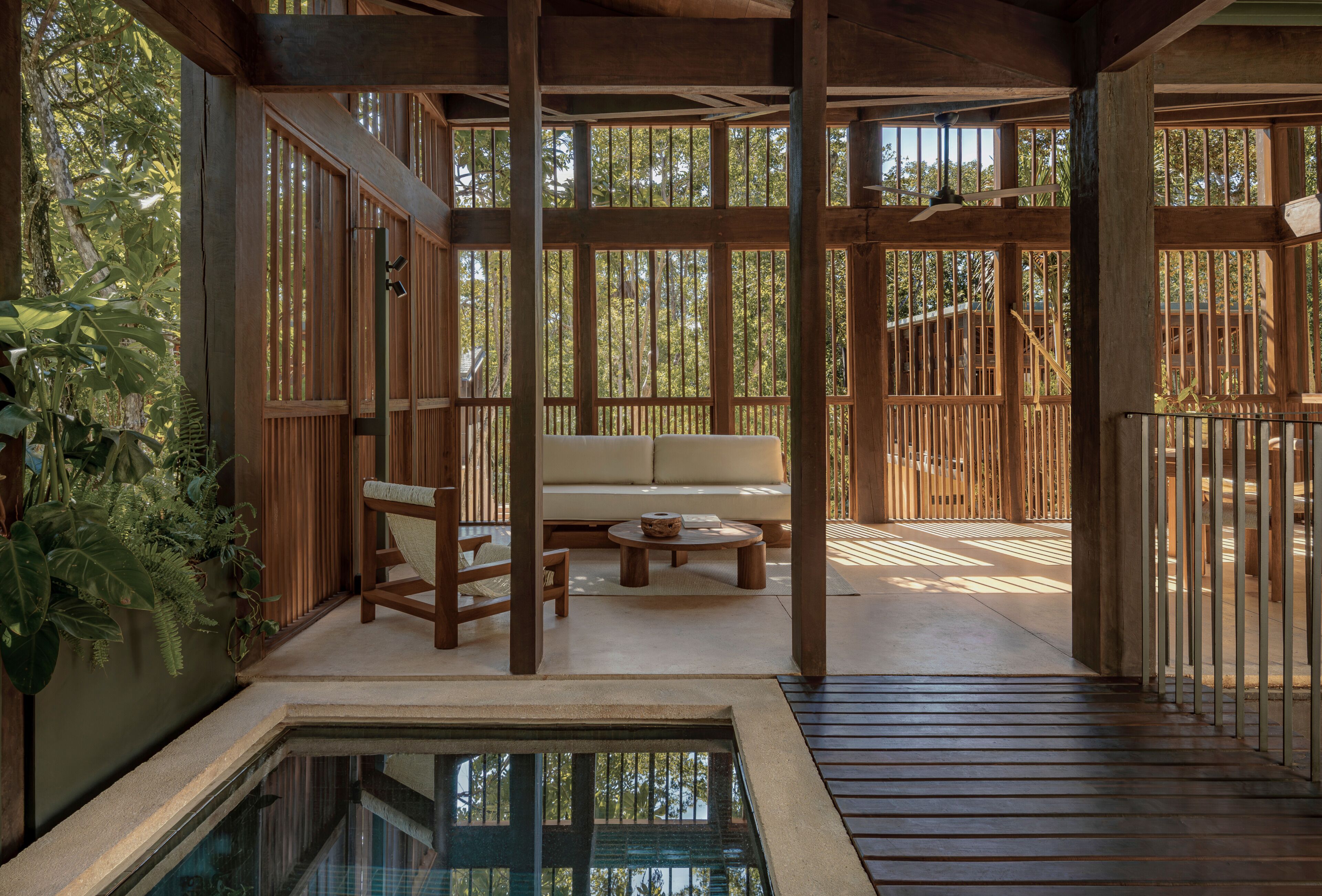 A wooden deck with a sofa and chairs, a small table, and a pool.