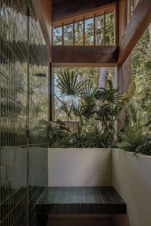 Une pièce avec vue sur la verdure, visible à travers une fenêtre, un banc carrelé et une structure de plafond en bois.