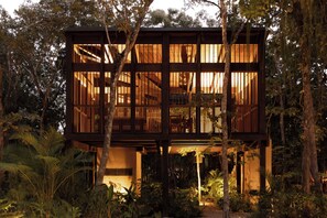 Een houten chalet met meerdere verdiepingen, omringd door dicht bos.