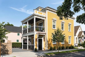 A two-story yellow building with a balcony, a stone wall, and a tree in the front yard. - Spacious 4bd House, New Bathrooms, Near King St. (Charleston)
