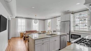 A modern kitchen with white cabinetry, a central island, and a built-in oven.