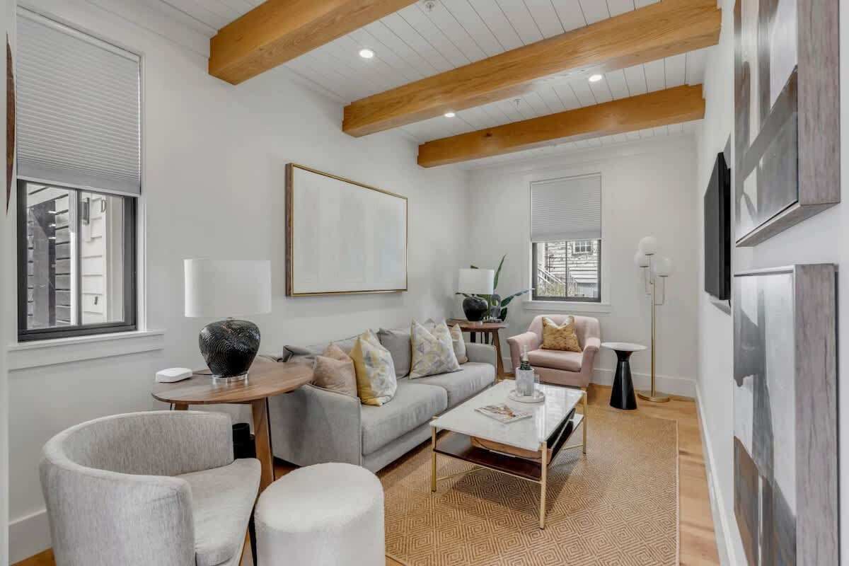 A modern living room with a sofa, armchairs, a coffee table, and a fireplace.