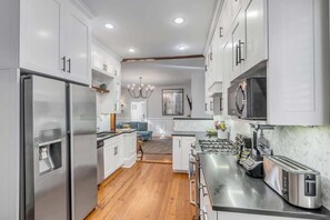 Una cocina moderna con electrodomésticos de acero inoxidable, armarios blancos y suelo de madera.
