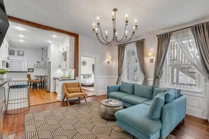 A modern living room with a blue sofa, a round coffee table, and a chandelier. - Downtown Suite in Pristine Historic Home (Charleston)