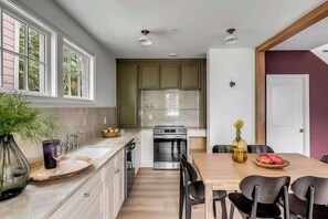 Eine moderne Küche mit einer großen Kochinsel, integrierten Geräten und einem Essbereich mit Holztisch und -stühlen.